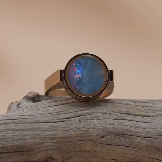 Australian opal unisex ring resting on driftwood, slow orbit showing the colour play in the stone