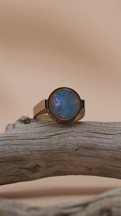 Australian opal unisex ring resting on driftwood, slow orbit showing the colour play in the stone