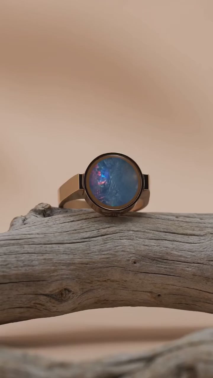 Australian opal unisex ring resting on driftwood, slow orbit showing the colour play in the stone