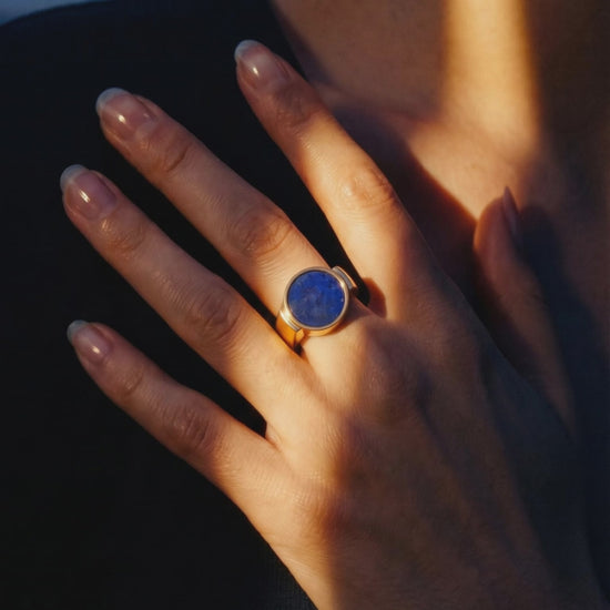 Lapis lazuli unisex signet ring worn on a hand resting at the collarbone in warm dusk light
