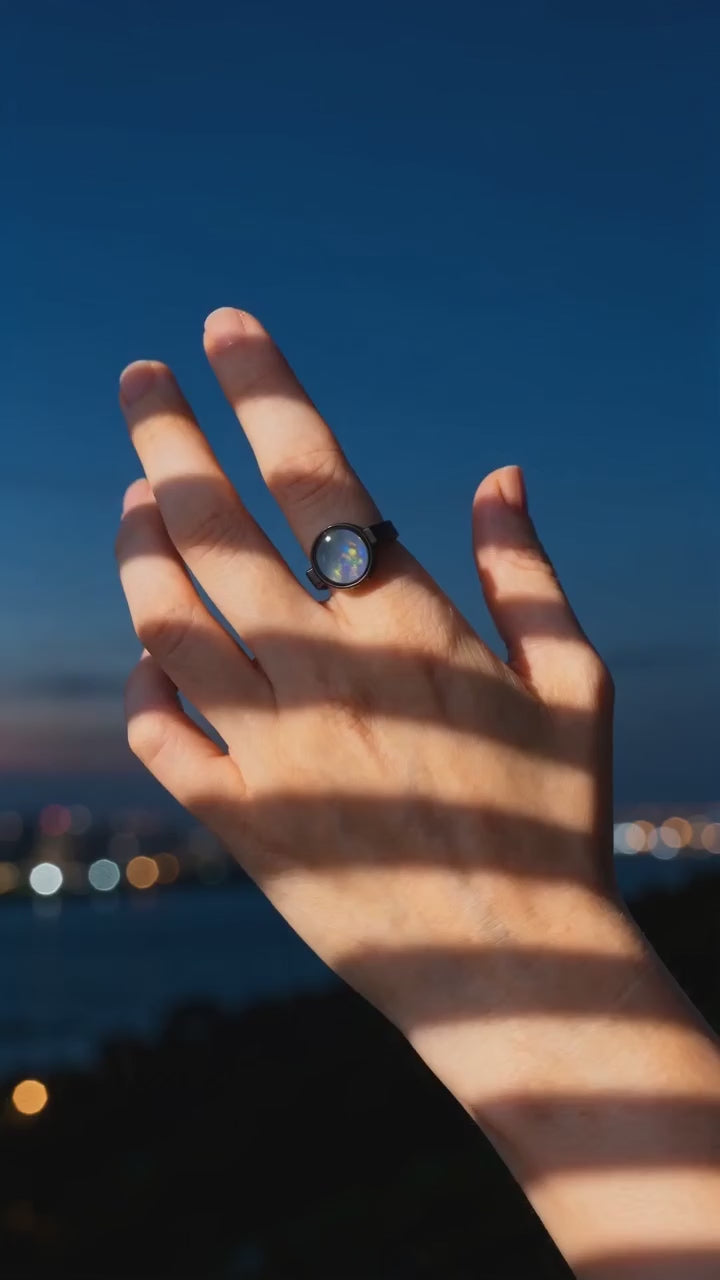 Australian opal unisex ring worn on a hand at blue hour, warm light falling across the skin