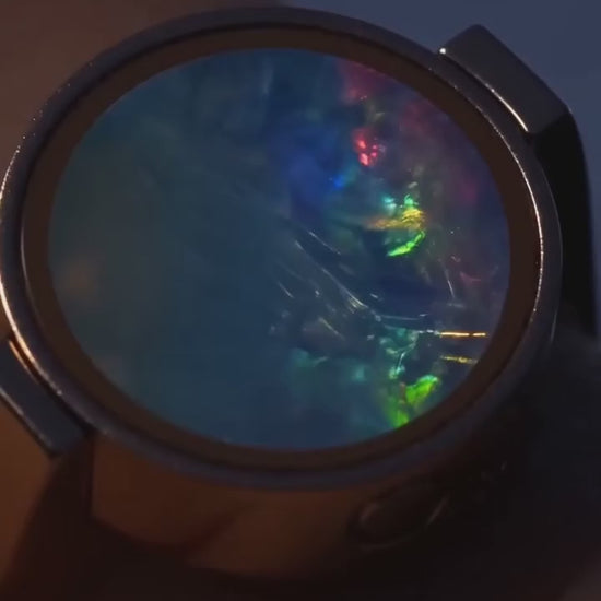 The Australian Opal Unisex Ring worn, its opal catching the light as the hand turns.