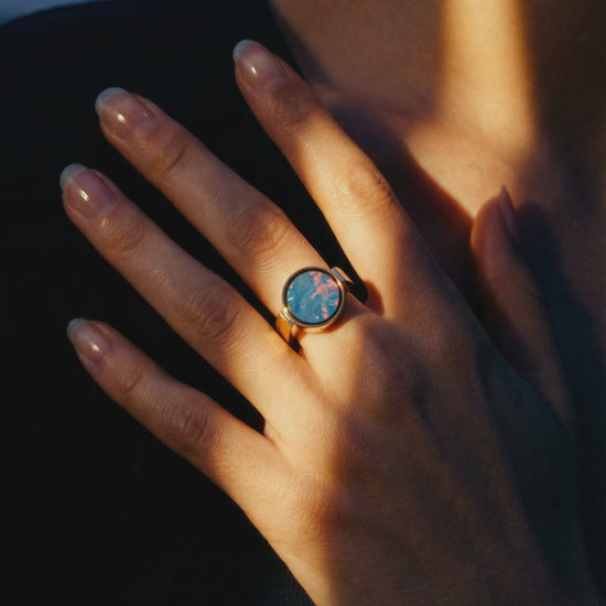 Australian opal unisex signet ring worn on a hand resting at the collarbone in warm dusk light