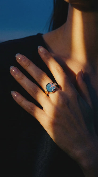Australian opal unisex signet ring worn on a hand resting at the collarbone in warm dusk light